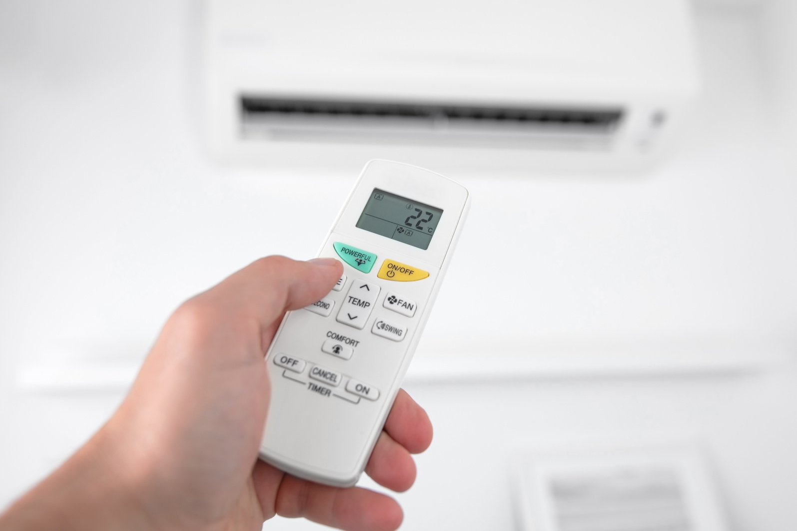 Man holding a modern AC unit remote.
