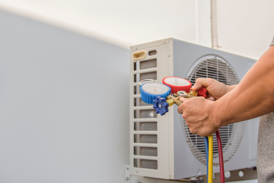 Air conditioning, HVAC service technician using gauges to check refrigerant and add refrigerant.